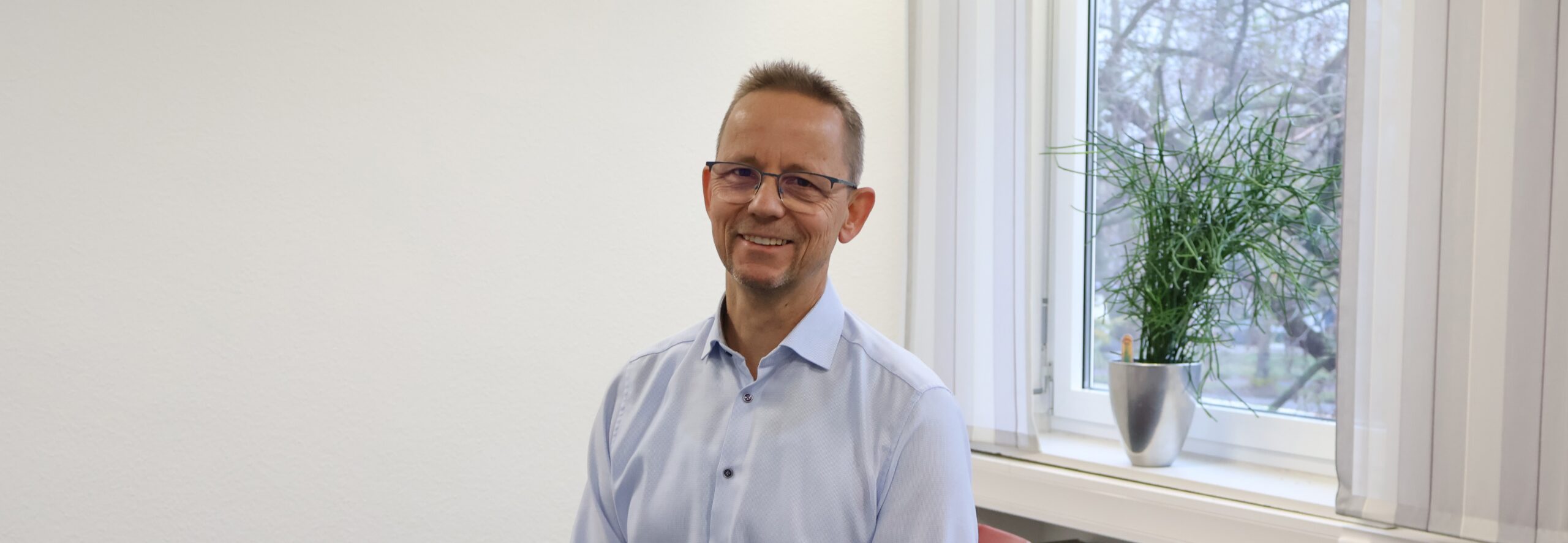 Mann sitzt in Büro und lächelt in die Kamera