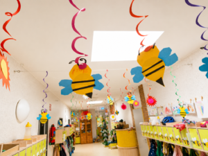 Aus Pappe gebastelte Bienen hängen von einer Decke in einem Kindergarten