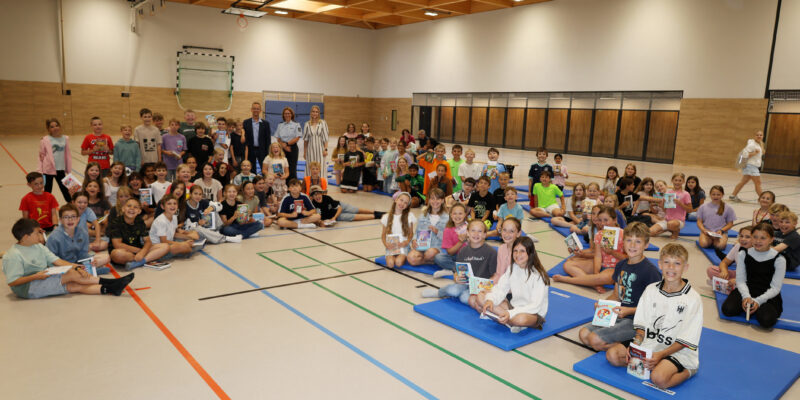 Viele Kinder sitzen auf dem Boden einer Turnhalle