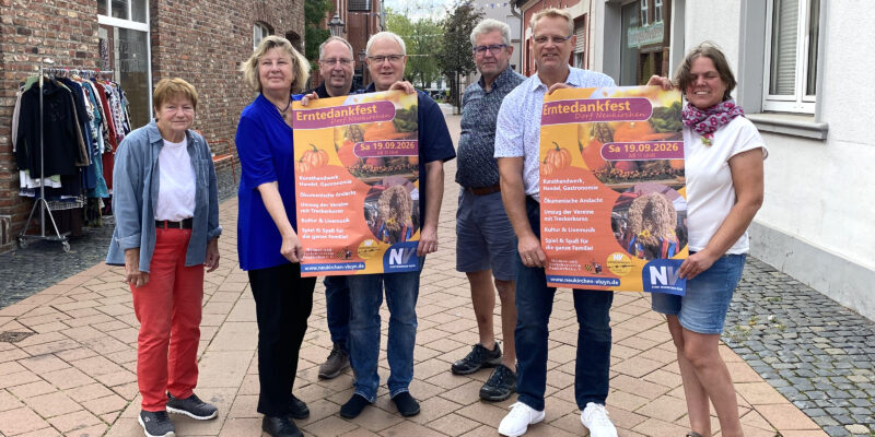 Menschen stehen in einer Fußgängerzone und präsentieren Werbeplakate für das Erntedankfest