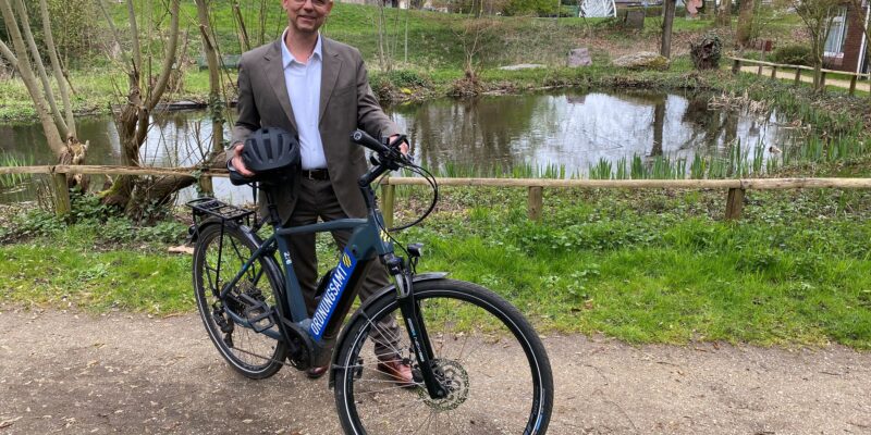 Ein Mann steht mit einem Fahrrad auf einem Weg.