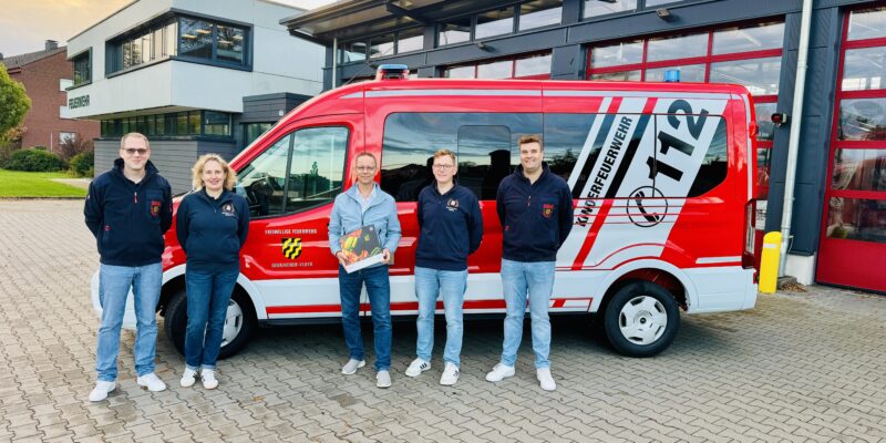 5 Personen stehen vor einem Mannschaftstransportfahrzeug der Feuerwehr