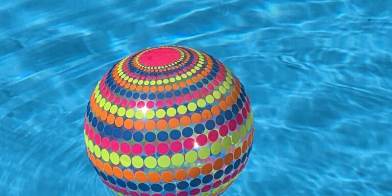 Ein bunter Wasserball schwimmt auf einer hellblauen Wasseroberfläche